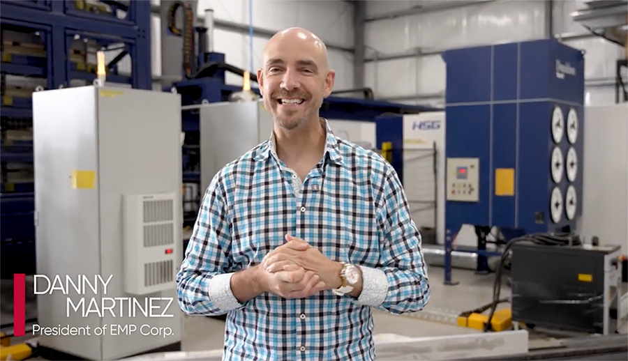Danny Martinez inside the EMP Warehouse, smiling, standing in front of machines